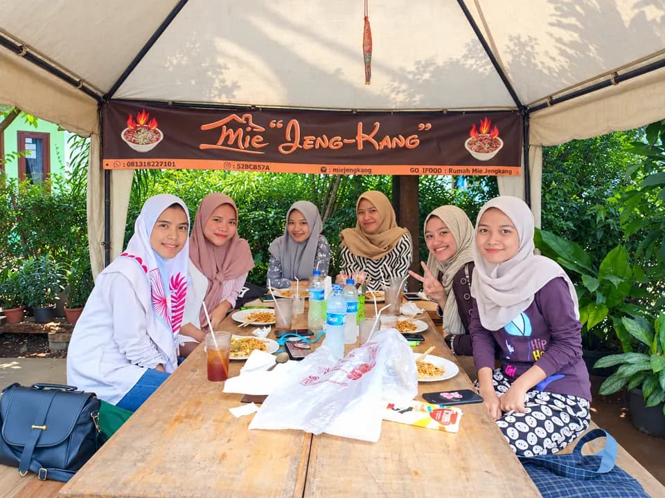 Enam perempuan menikmati mie di bawah tenda Mie Jeng-Kang